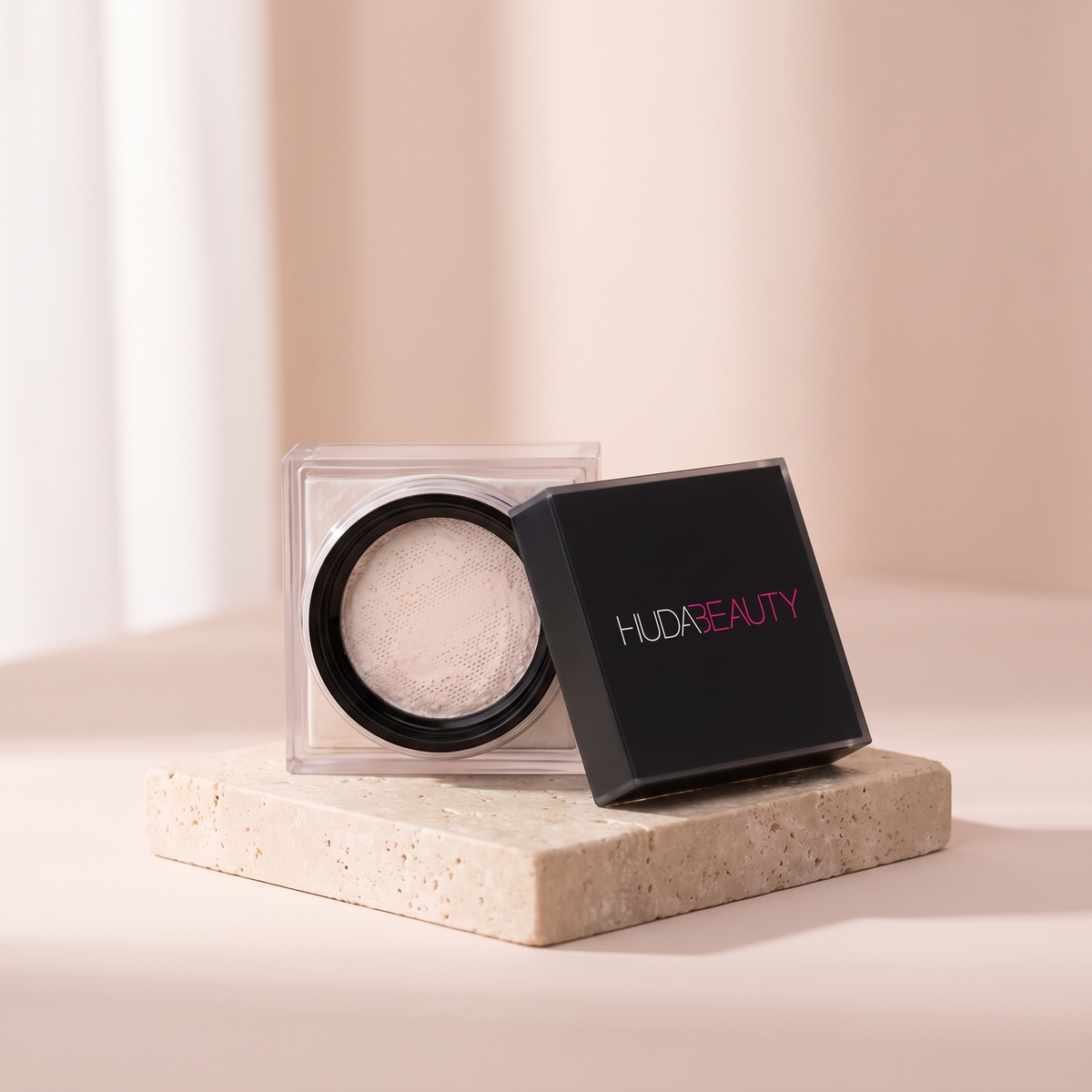 Huda Beauty Easy Bake Setting Powder styled on travertine pedestal, blush studio