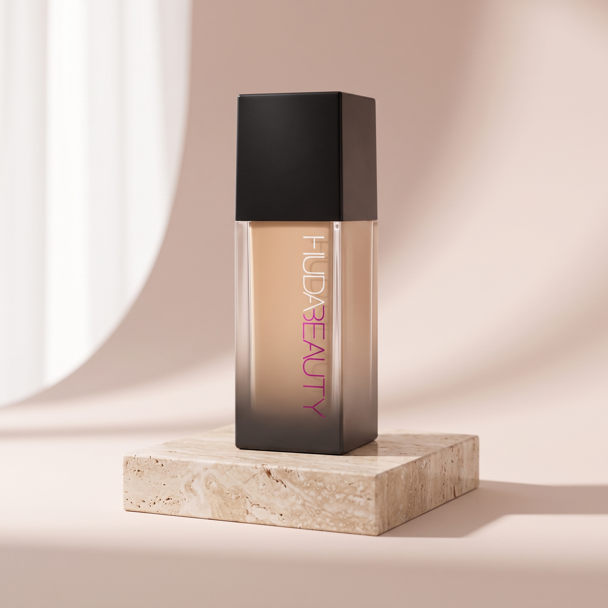 Huda Beauty Faux Filter Foundation styled on travertine pedestal, blush studio