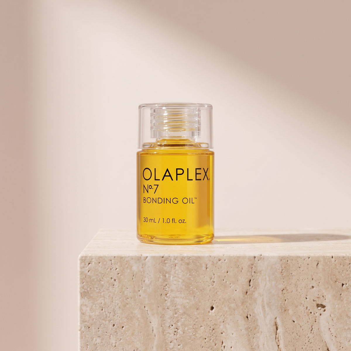 Olaplex No.7 Bonding Oil 30mL styled on travertine pedestal, blush studio
