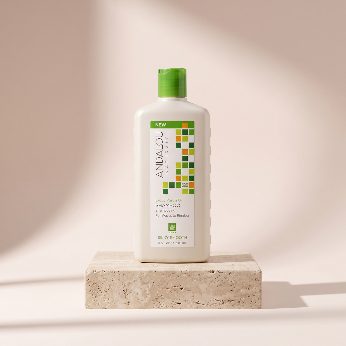 Andalou Naturals Exotic Marula Oil Silky Smooth Shampoo 340 ml styled on travertine pedestal, blush studio