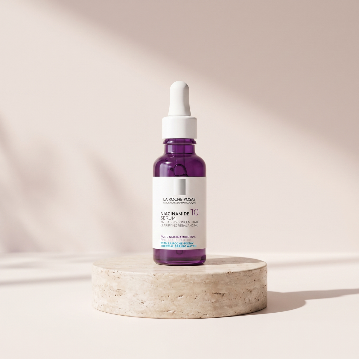 PURE Niacinamide 10 Serum 30 ml styled on travertine pedestal, blush studio